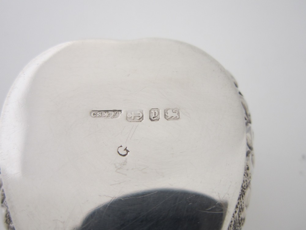 A heart-shaped sterling silver trinket box with detailed embossed foliate scrollwork and a scalloped rim. View VI