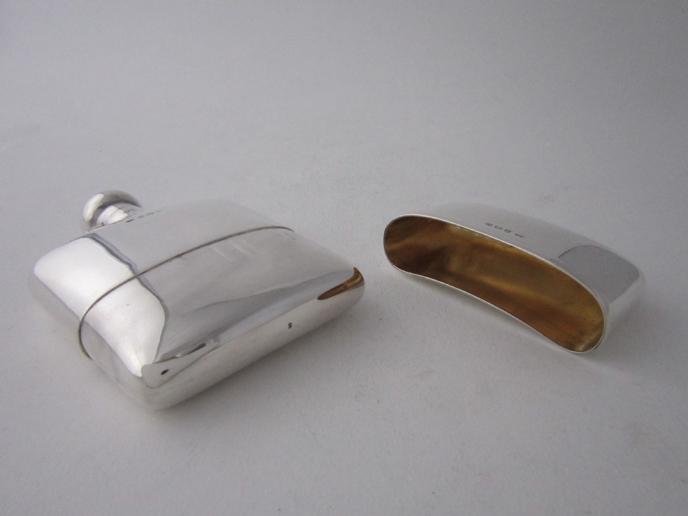 A curved George V sterling silver hip flask featuring a detachable lower cup and a round bayonet cap against a plain studio background. View III