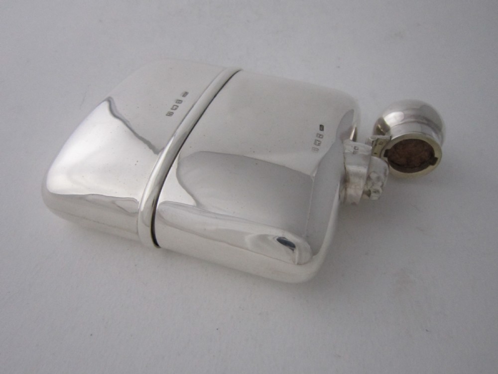 A curved George V sterling silver hip flask featuring a detachable lower cup and a round bayonet cap against a plain studio background. View IV