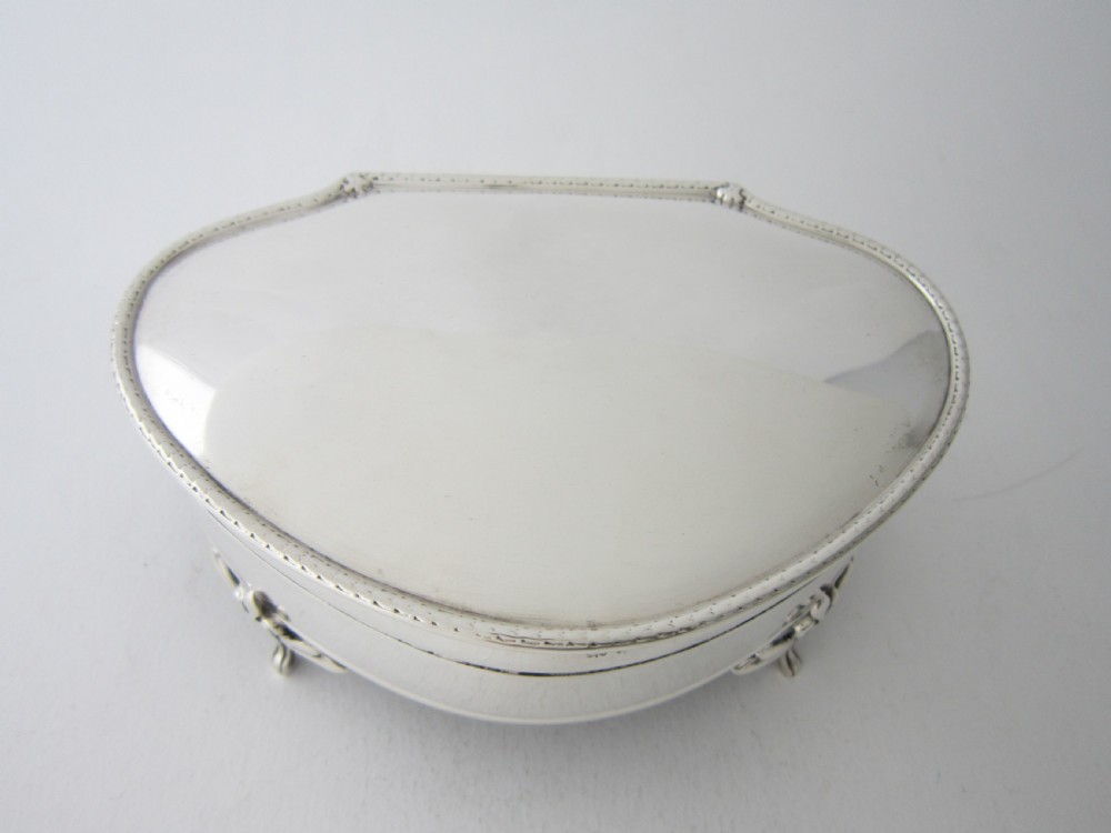 An antique George V sterling silver trinket box with a smooth shaped hinged lid, beaded trim, and four raised feet.