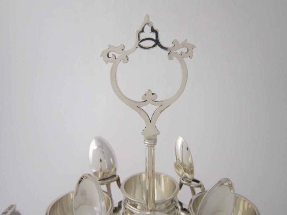 A George V sterling silver egg cruet set featuring four egg cups and matching spoons arranged on an oval silver tray with a central loop handle. View II