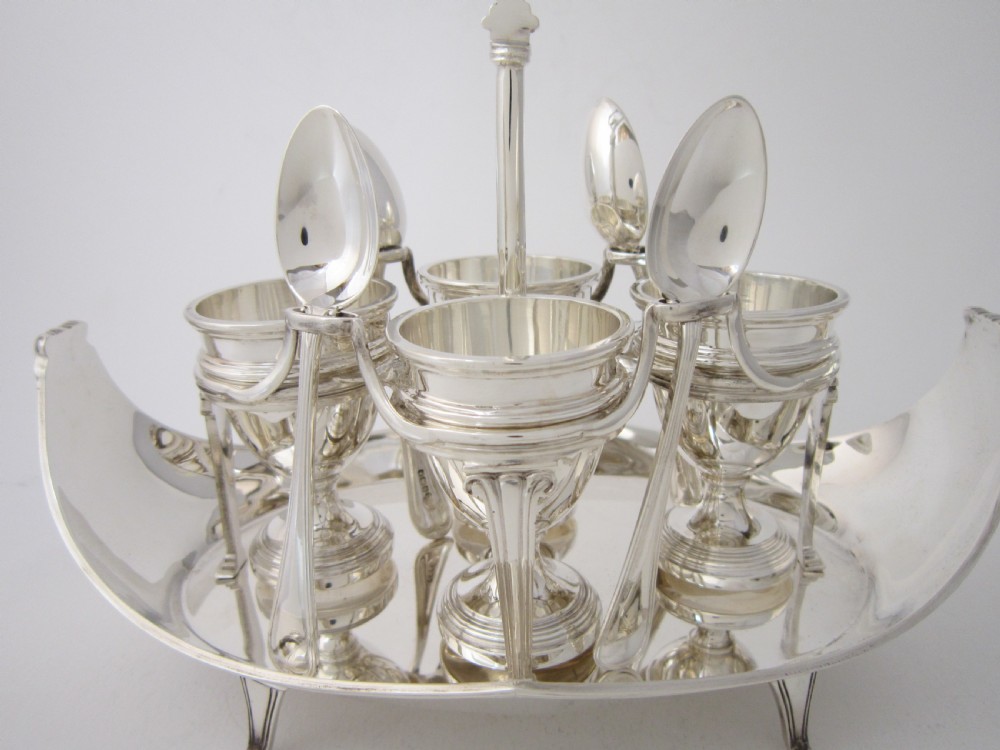 A George V sterling silver egg cruet set featuring four egg cups and matching spoons arranged on an oval silver tray with a central loop handle. View III