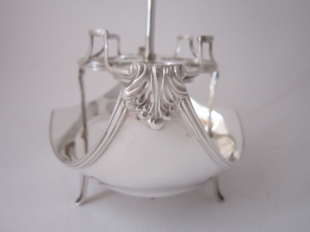 A George V sterling silver egg cruet set featuring four egg cups and matching spoons arranged on an oval silver tray with a central loop handle. View V