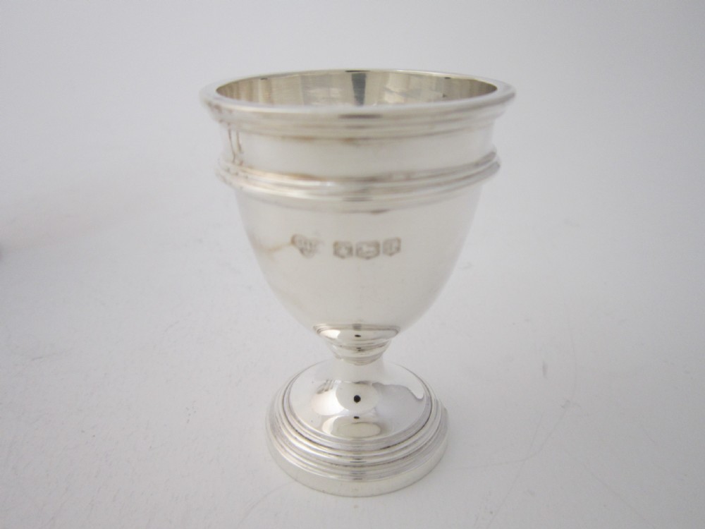 A George V sterling silver egg cruet set featuring four egg cups and matching spoons arranged on an oval silver tray with a central loop handle. View VII