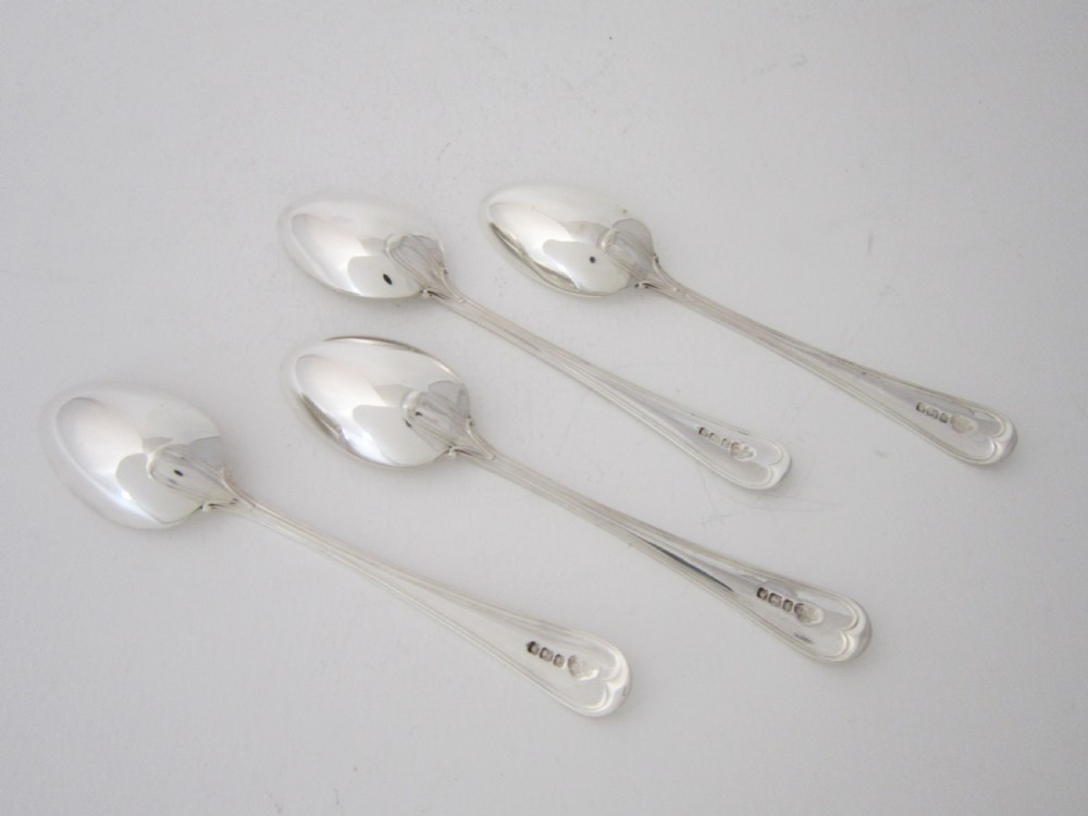A George V sterling silver egg cruet set featuring four egg cups and matching spoons arranged on an oval silver tray with a central loop handle. View X