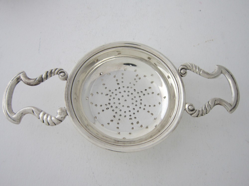 A solid sterling silver double-handled tea strainer with a pierced star bowl pattern and scrolled side handles. View III
