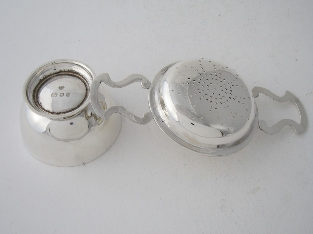 A solid sterling silver double-handled tea strainer with a pierced star bowl pattern and scrolled side handles. View IV