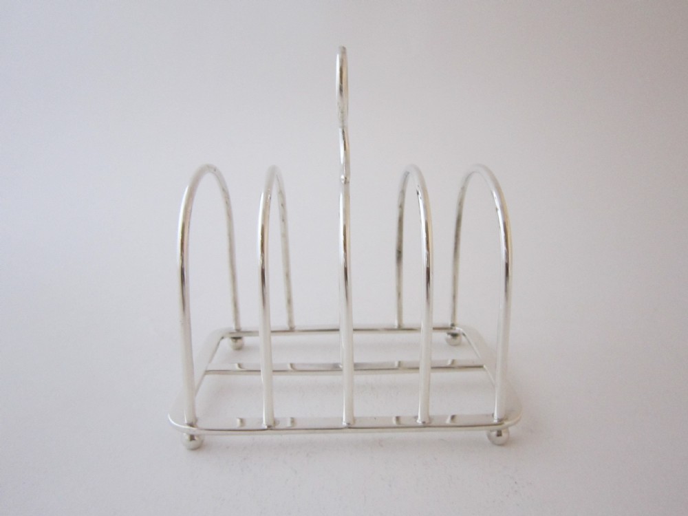 A Victorian sterling silver toast rack featuring arched wire dividers, a top loop handle, and four small ball feet. View IV