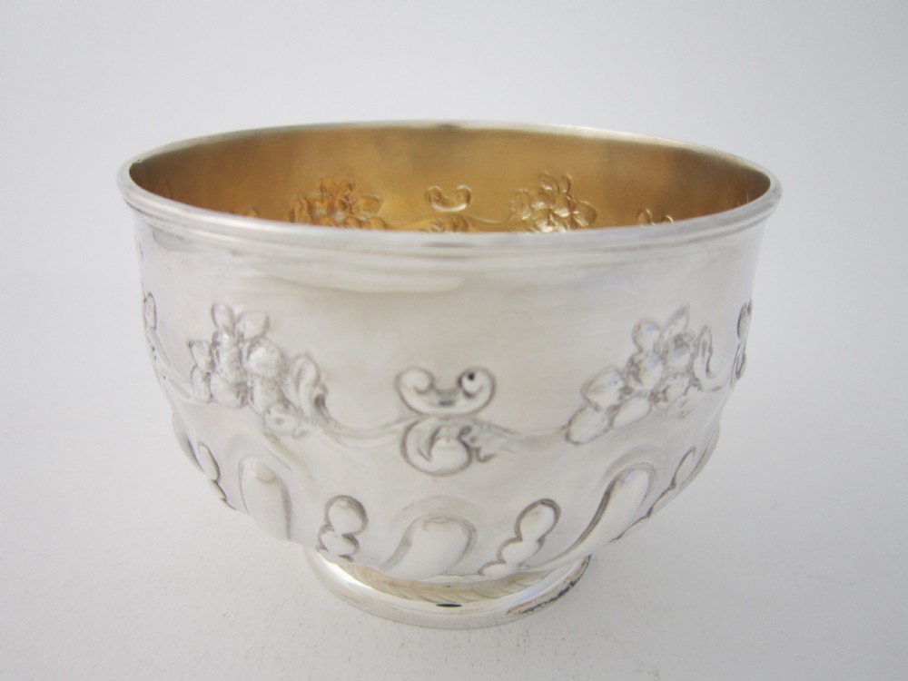An Edwardian sterling silver bowl featuring repousse scroll motifs, a gilded interior, a raised foot rim, and visible English hallmarks. View II