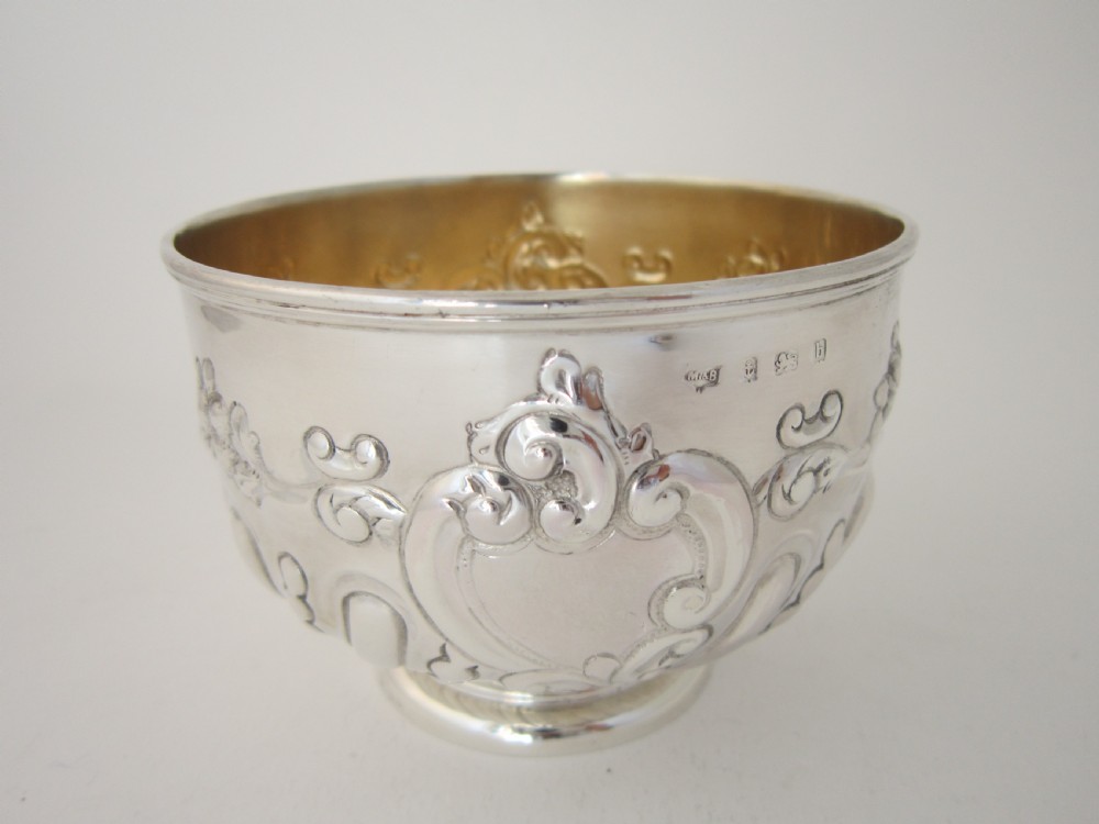 An Edwardian sterling silver bowl featuring repousse scroll motifs, a gilded interior, a raised foot rim, and visible English hallmarks. View IV