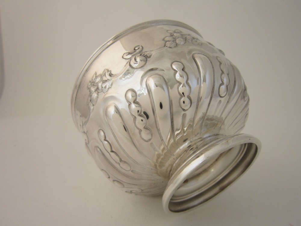 An Edwardian sterling silver bowl featuring repousse scroll motifs, a gilded interior, a raised foot rim, and visible English hallmarks. View VI