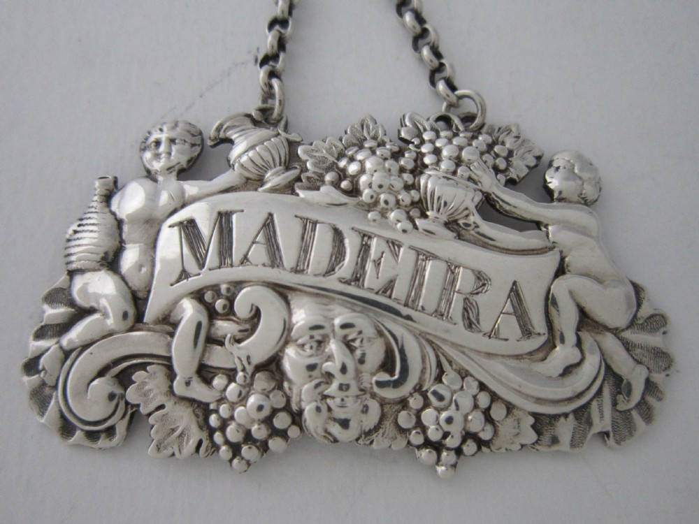 A pair of Scottish George III sterling silver decanter labels engraved with Madeira and Port, featuring relief motifs of cherubs, grapes, and scrollwork on hanging chains. View III