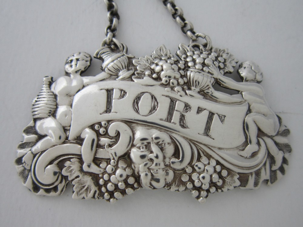 A pair of Scottish George III sterling silver decanter labels engraved with Madeira and Port, featuring relief motifs of cherubs, grapes, and scrollwork on hanging chains. View VIII