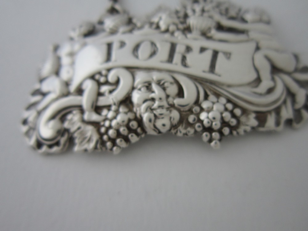 A pair of Scottish George III sterling silver decanter labels engraved with Madeira and Port, featuring relief motifs of cherubs, grapes, and scrollwork on hanging chains. View XI
