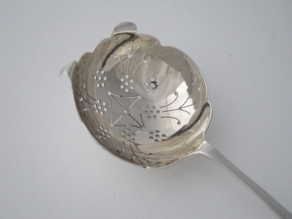 A sterling silver tea strainer featuring a pierced bowl with geometric patterns and an openwork handle. View III