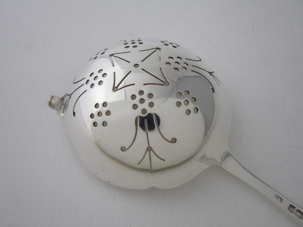 A sterling silver tea strainer featuring a pierced bowl with geometric patterns and an openwork handle. View VI