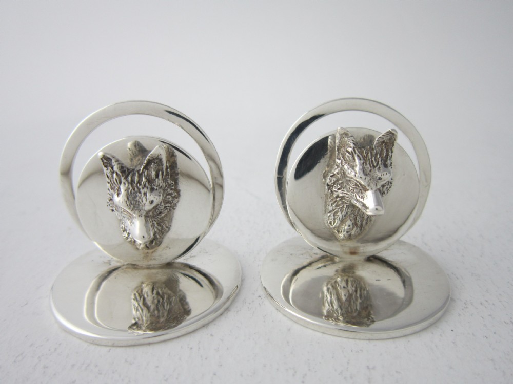 A pair of sterling silver place card holders featuring sculpted fox heads mounted on circular silver bases. View VII