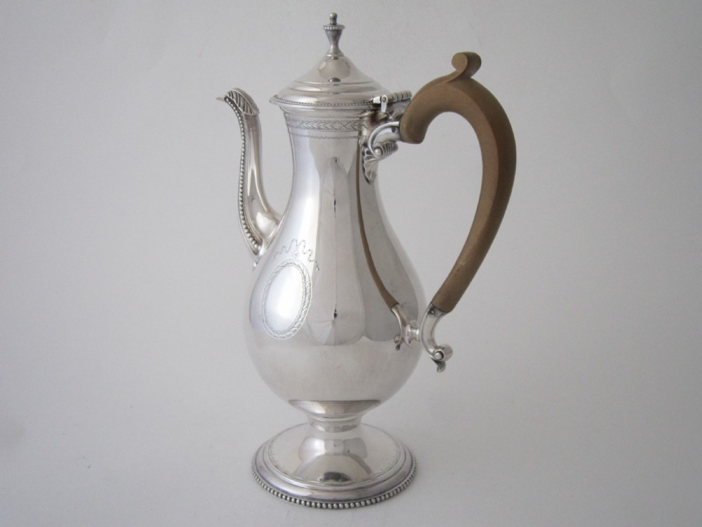 A five-piece sterling silver tea and coffee set featuring carved wooden handles, engraved oval cartouches, a teapot with stand, coffee pot, cream jug, and sugar basket. View II