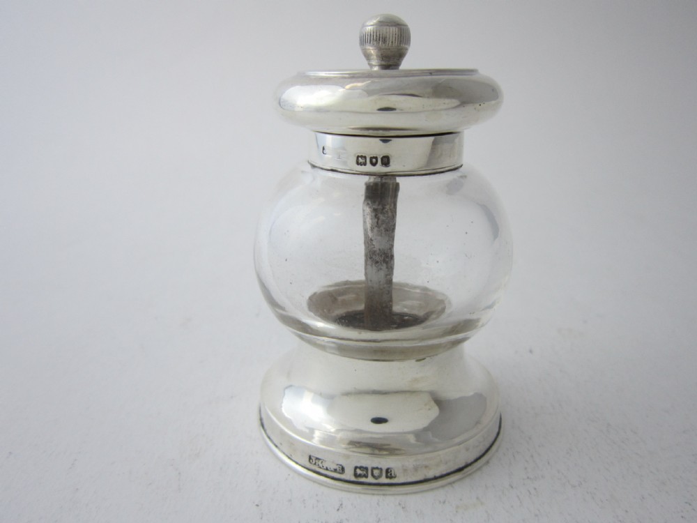 Victorian sterling silver and clear glass pepper grinder featuring hallmarked silver rims and a turned top knob.