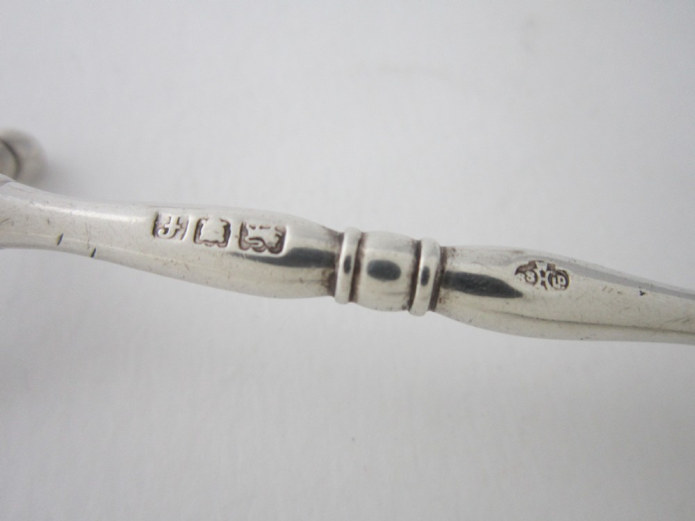 A pair of antique sterling silver knife rests featuring turned central bars and cross-shaped end supports with ball feet. View IV