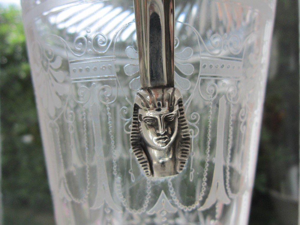 An antique Victorian claret jug featuring a clear etched glass body with cut geometric patterns and an engraved sterling silver collar and handle. View VII