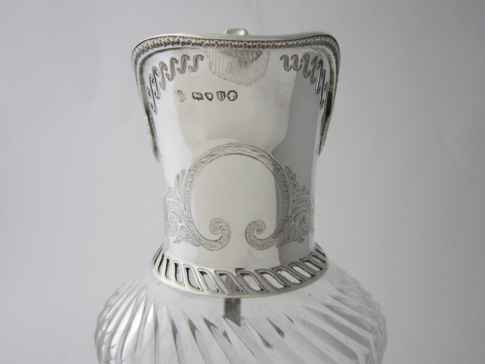 An antique Victorian claret jug featuring a clear etched glass body with cut geometric patterns and an engraved sterling silver collar and handle. View XI