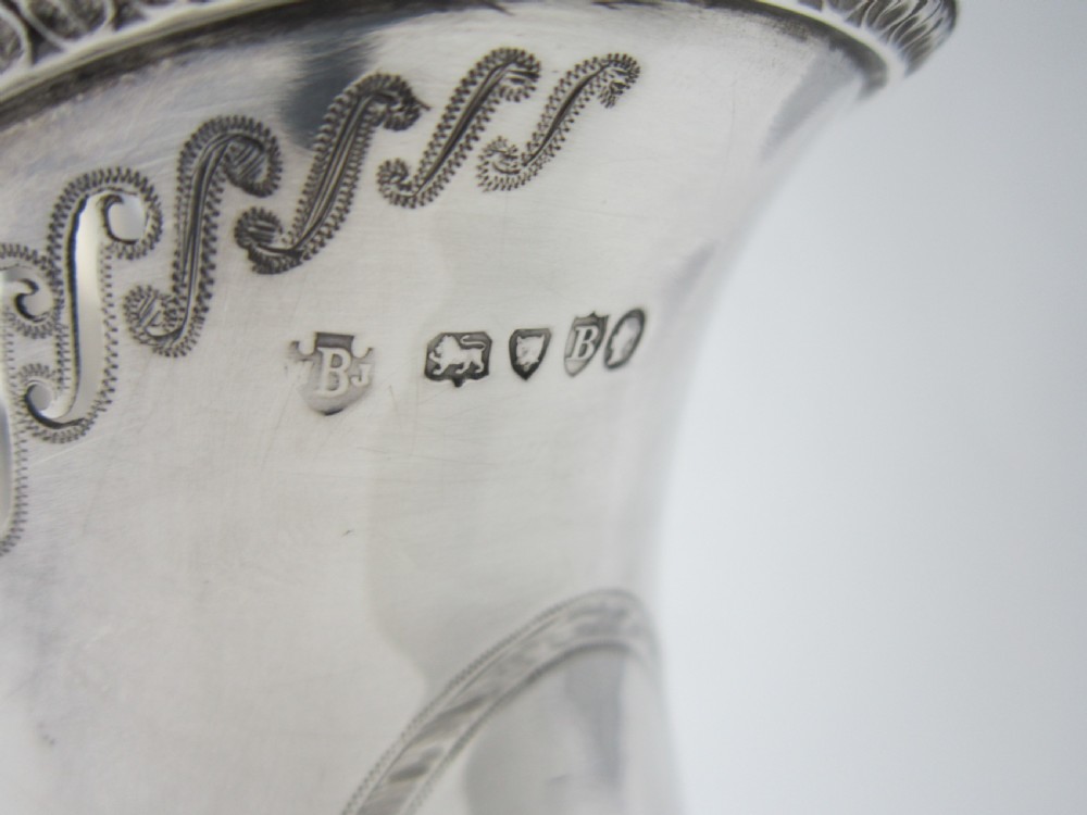 An antique Victorian claret jug featuring a clear etched glass body with cut geometric patterns and an engraved sterling silver collar and handle. View XII