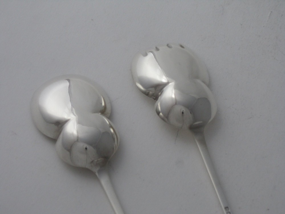 A pair of Edwardian sterling silver salad servers with chased foliate handles and shaped lobed bowls, dating to 1903. View VI