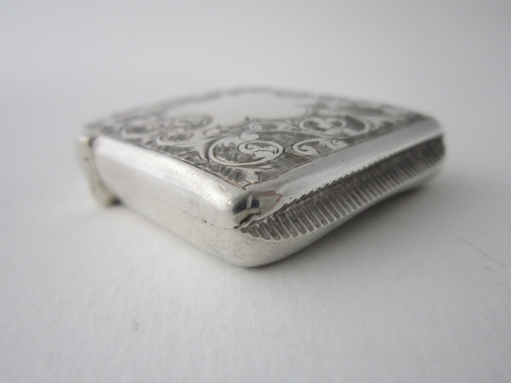 An antique sterling silver vesta case featuring hand-engraved foliate scrollwork, a vacant shield cartouche, and an attached suspension ring. View IV