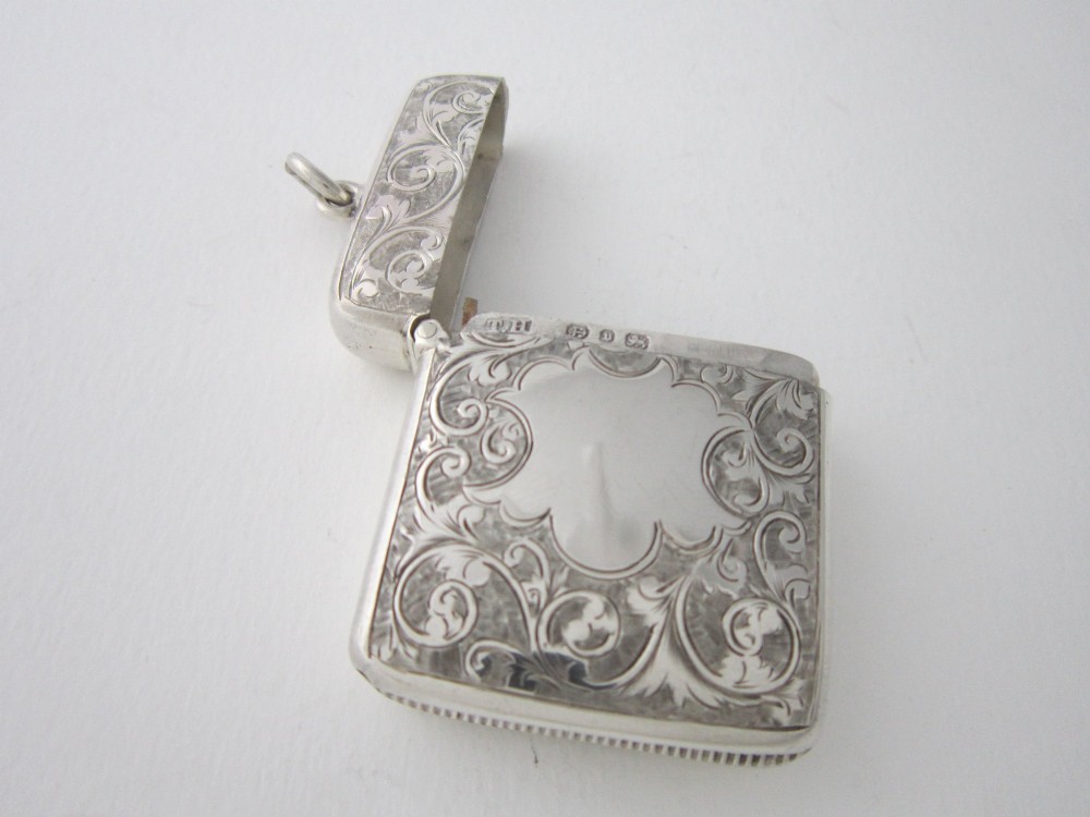 An antique sterling silver vesta case featuring hand-engraved foliate scrollwork, a vacant shield cartouche, and an attached suspension ring. View V