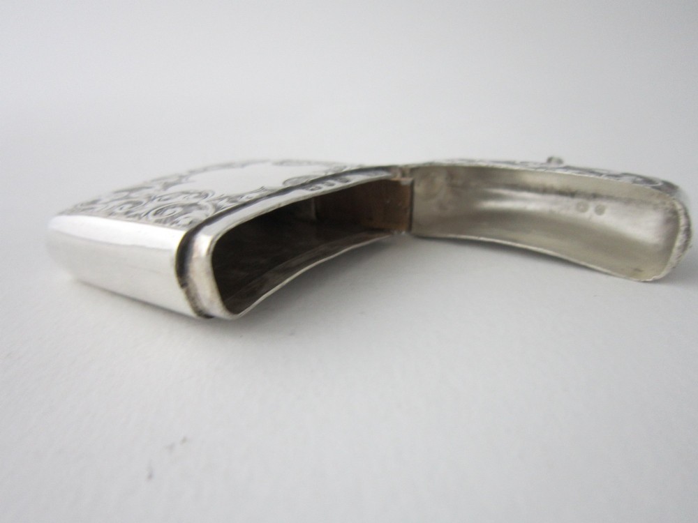An antique sterling silver vesta case featuring hand-engraved foliate scrollwork, a vacant shield cartouche, and an attached suspension ring. View VI