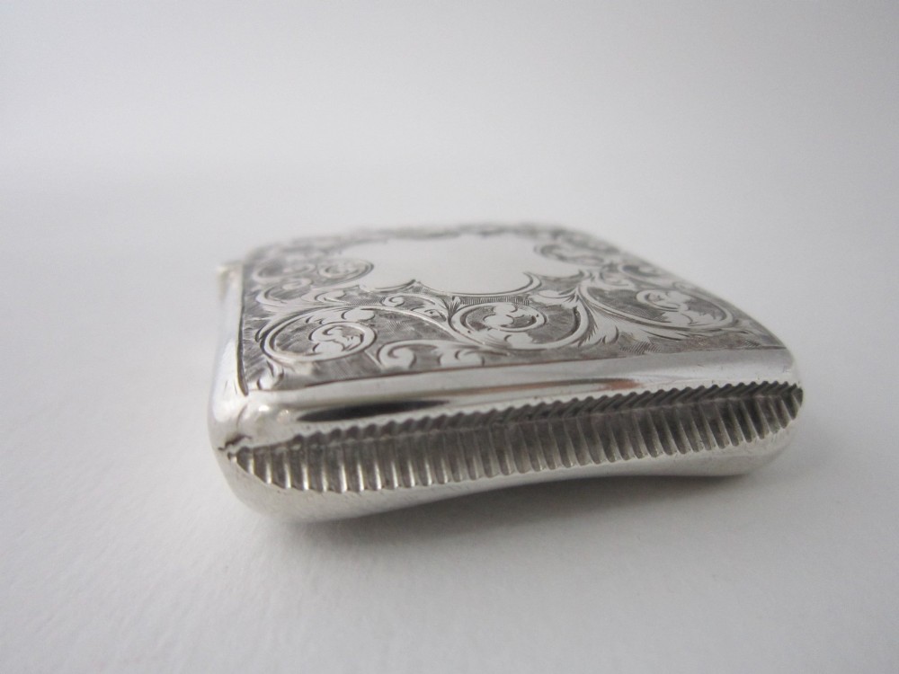 An antique sterling silver vesta case featuring hand-engraved foliate scrollwork, a vacant shield cartouche, and an attached suspension ring. View VIII