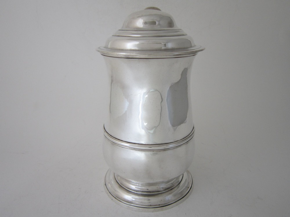 An antique George III sterling silver lidded tankard featuring a moulded dome lid, scroll handle, central girdle band, and spreading base. View III