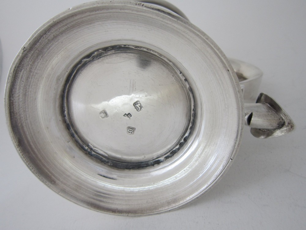 An antique George III sterling silver lidded tankard featuring a moulded dome lid, scroll handle, central girdle band, and spreading base. View VIII