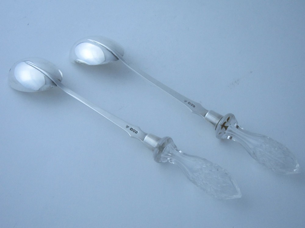 A pair of Edwardian sterling silver salad servers featuring faceted cut glass handles and rat tail detailing on the bowls. View IV