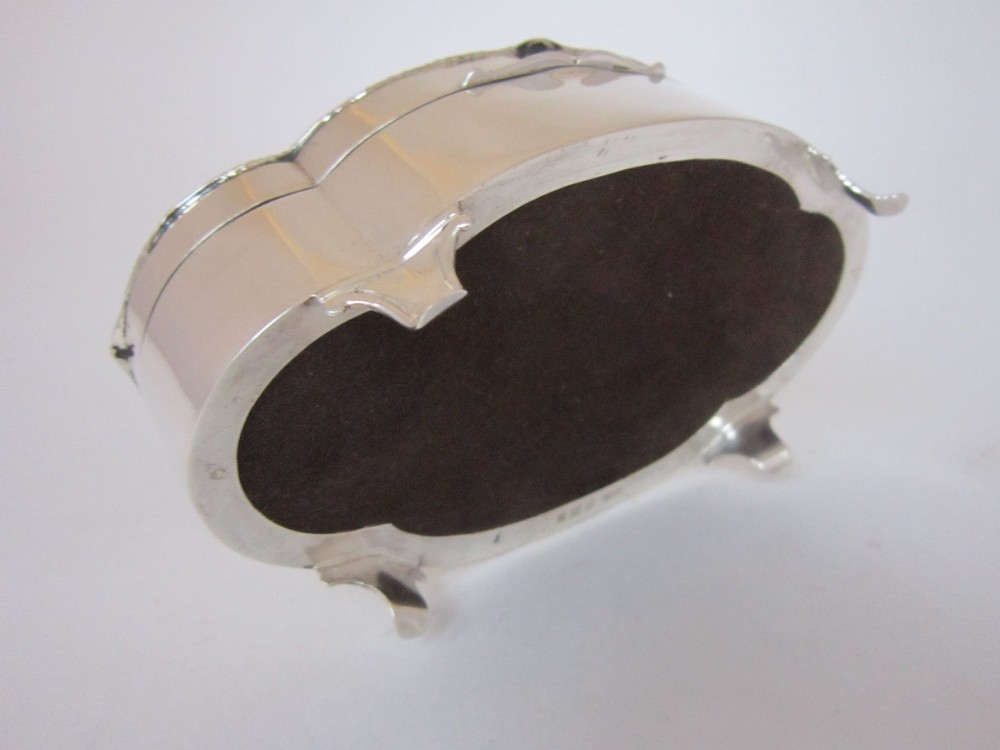 A shaped sterling silver trinket box featuring a dark tortoiseshell lid inlaid with a silver flower basket and ribbon swags, resting on four small feet. View VII