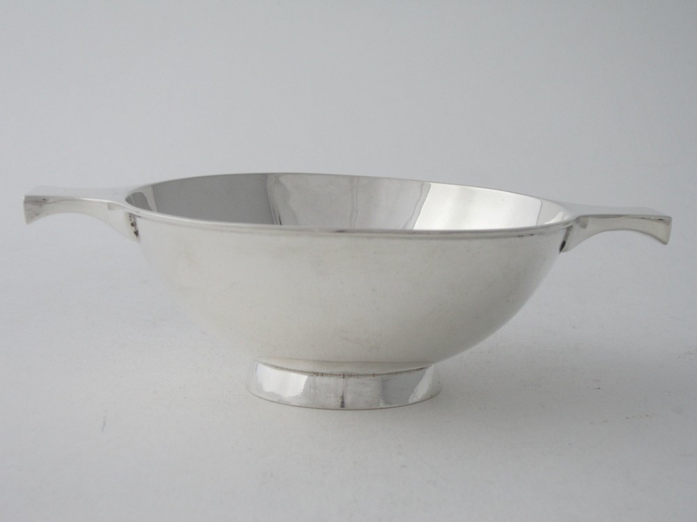 A polished sterling silver Scottish quaich featuring a shallow circular bowl, raised foot, and twin flat handles.