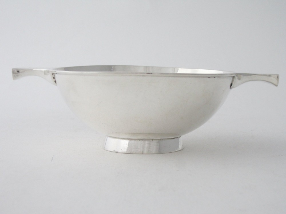 A polished sterling silver Scottish quaich featuring a shallow circular bowl, raised foot, and twin flat handles. View III