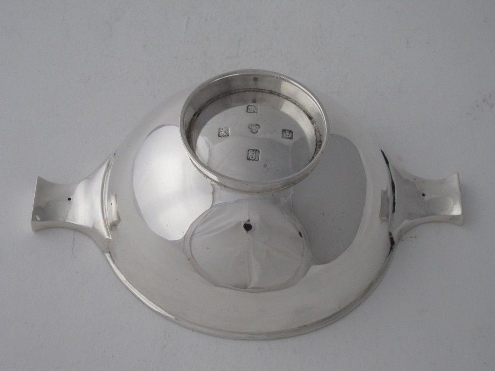 A polished sterling silver Scottish quaich featuring a shallow circular bowl, raised foot, and twin flat handles. View IV