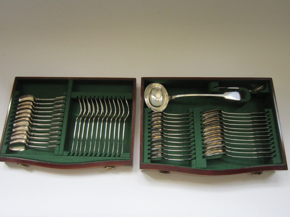 An open Victorian mahogany canteen chest fitted with drawers displaying a full sterling silver fiddle pattern cutlery service lined in green fabric. View IV