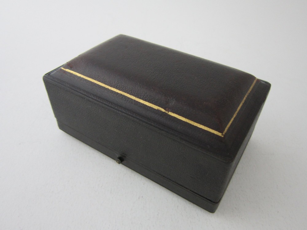 A pair of ornate Victorian sterling silver napkin rings featuring embossed acanthus leaves and cartouches inside a velvet-lined black presentation box. View II