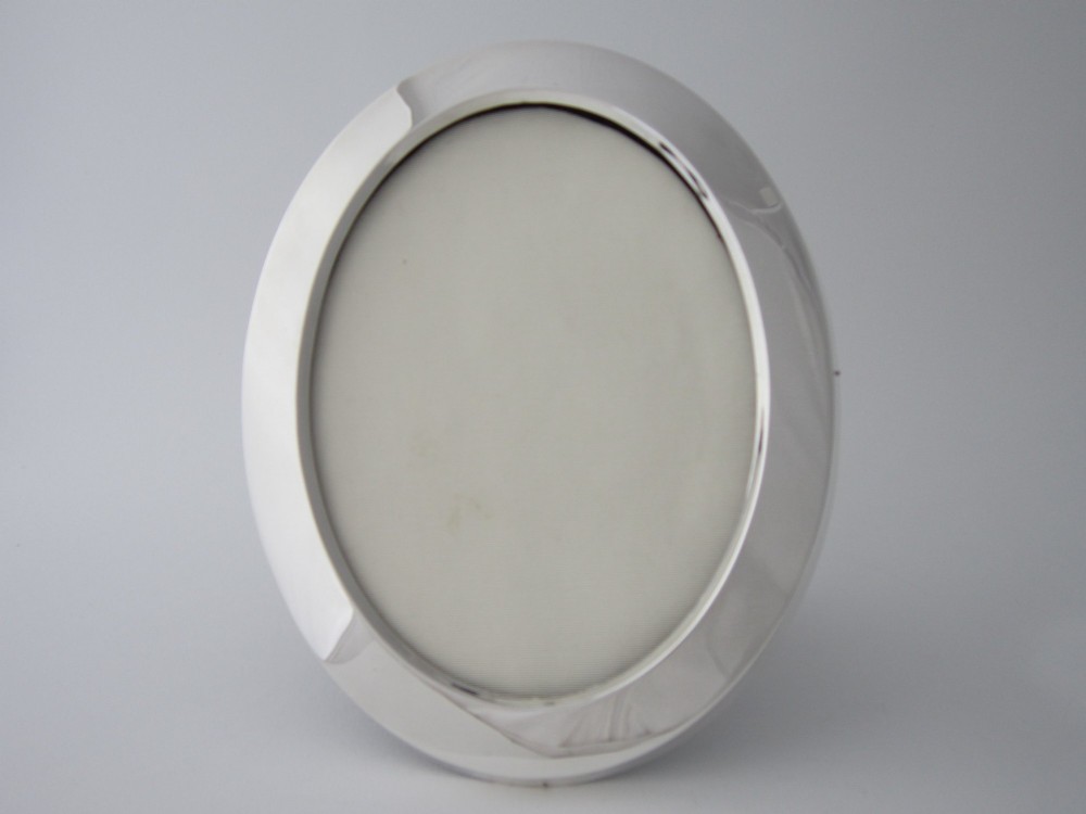 An oval sterling silver photograph frame featuring a smooth, polished border.