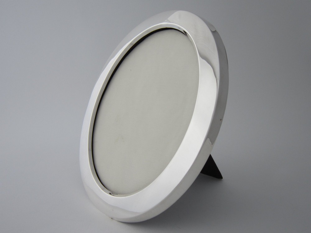 An oval sterling silver photograph frame featuring a smooth, polished border. View II