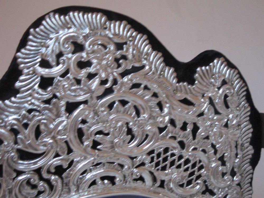 An antique Victorian double sterling silver photograph frame featuring intricate pierced repousse scrollwork and dark velvet backing. View III