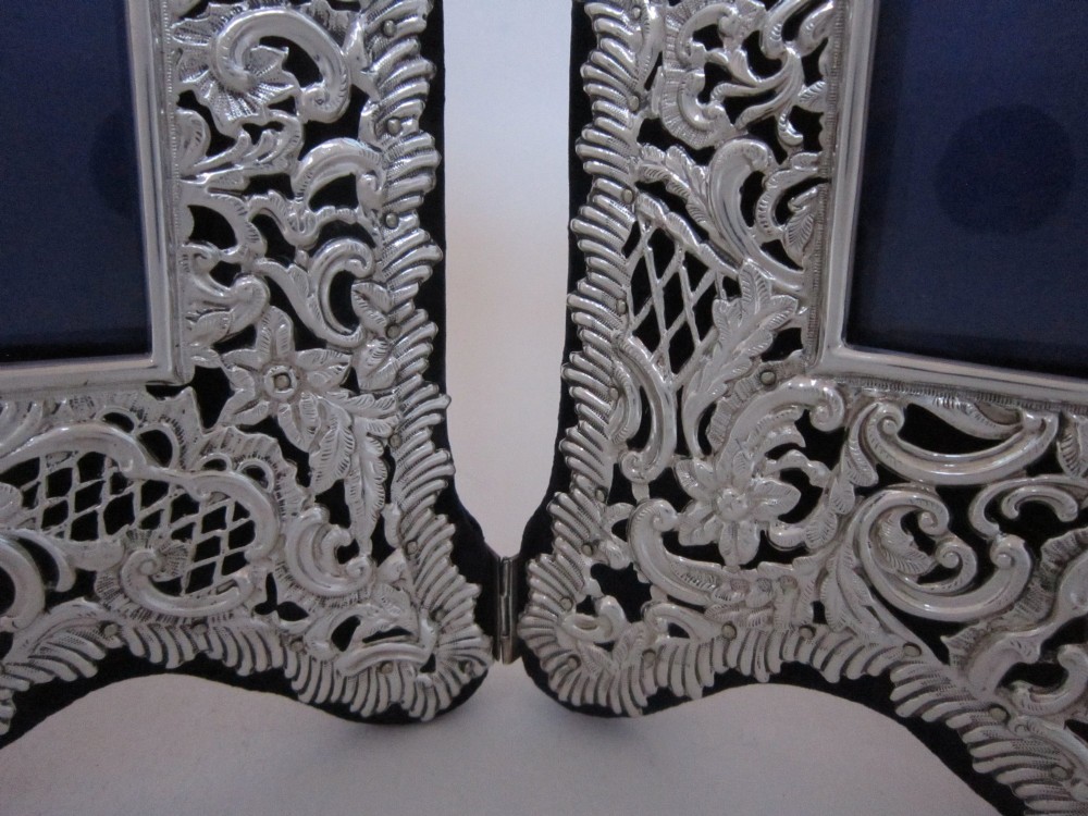 An antique Victorian double sterling silver photograph frame featuring intricate pierced repousse scrollwork and dark velvet backing. View V