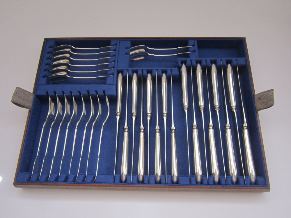 An open wooden canteen box lined with blue fabric displaying a complete set of Victorian sterling silver fiddle pattern cutlery. View II
