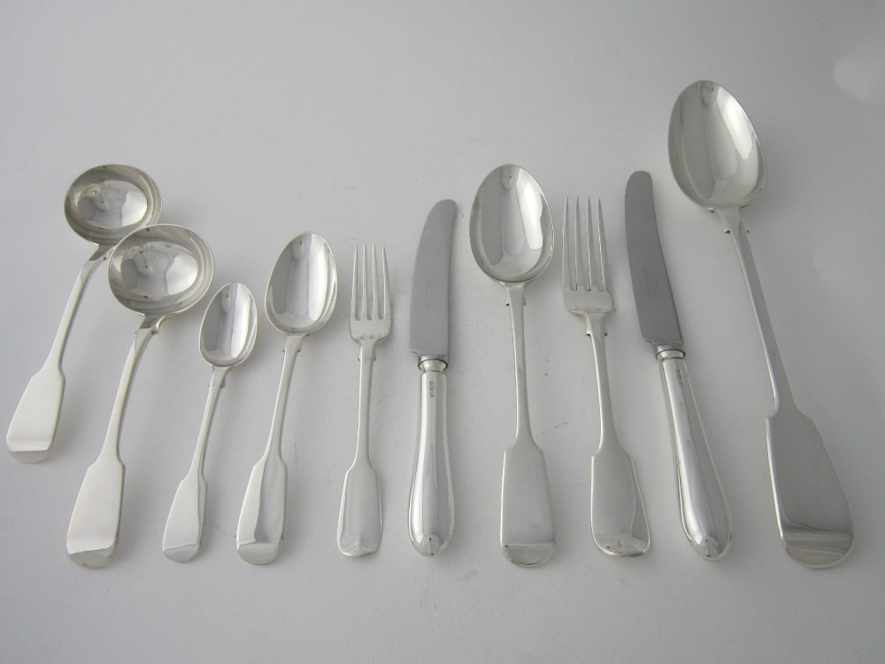 An open wooden canteen box lined with blue fabric displaying a complete set of Victorian sterling silver fiddle pattern cutlery. View V