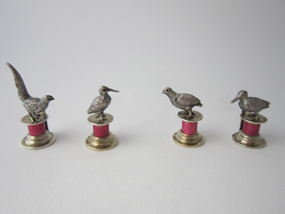 A set of four Edwardian sterling silver place card holders featuring pink guilloche enamel columns topped with sculpted game birds inside a fitted presentation box. View II