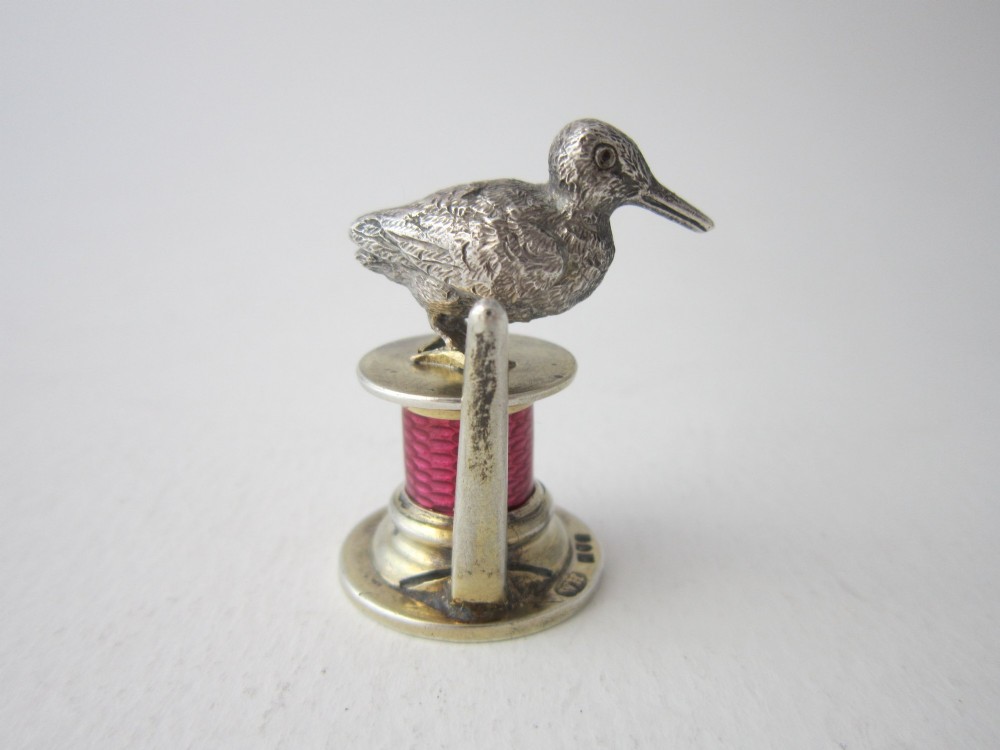 A set of four Edwardian sterling silver place card holders featuring pink guilloche enamel columns topped with sculpted game birds inside a fitted presentation box. View V