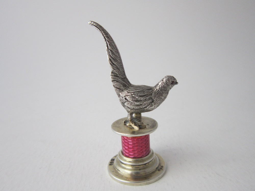 A set of four Edwardian sterling silver place card holders featuring pink guilloche enamel columns topped with sculpted game birds inside a fitted presentation box. View XII
